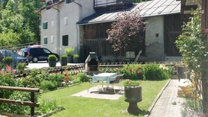 Un edificio con patio giardino, area salotto all'aperto e barbecue.