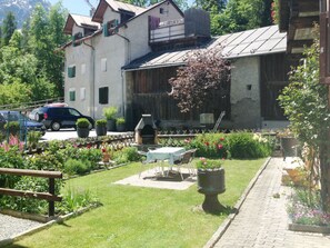 Ein Gebäude mit Garten-Terrasse, Sitzgelegenheiten im Freien und einem Barbereich.