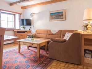 Ein gemütliches Wohnzimmer mit einem braunen Sofa, einem Holztisch, einem Fernseher und einem Bild an der Wand.