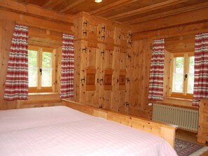 A wooden cabin bedroom with a bed, windows, and curtains. - Chasa Städler, (Zernez) by Interhome (Zernez)