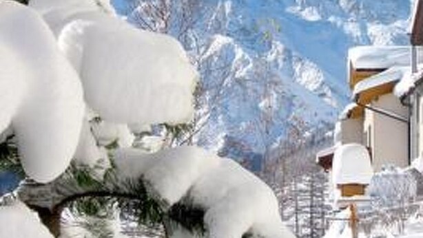 Un paisaje montañoso nevado con un edificio en primer plano.