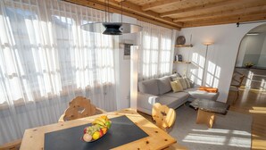 Un soggiorno moderno con un tavolo da pranzo in legno, un divano e un'area cucina sullo sfondo.