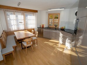 Una cocina moderna con una mesa de comedor de madera, sillas y un horno empotrado.