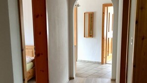 Un corridoio con porte in legno, pavimento piastrellato e uno specchio a parete.