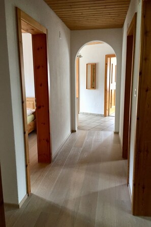 Ein Flur mit Holztüren, Fliesenboden und einem Spiegel an der Wand.