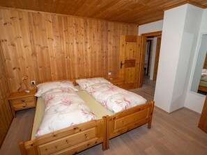 Ein Schlafzimmer mit Holzwandverkleidung, einem Doppelbett, Nachttischen und einem Kleiderschrank.