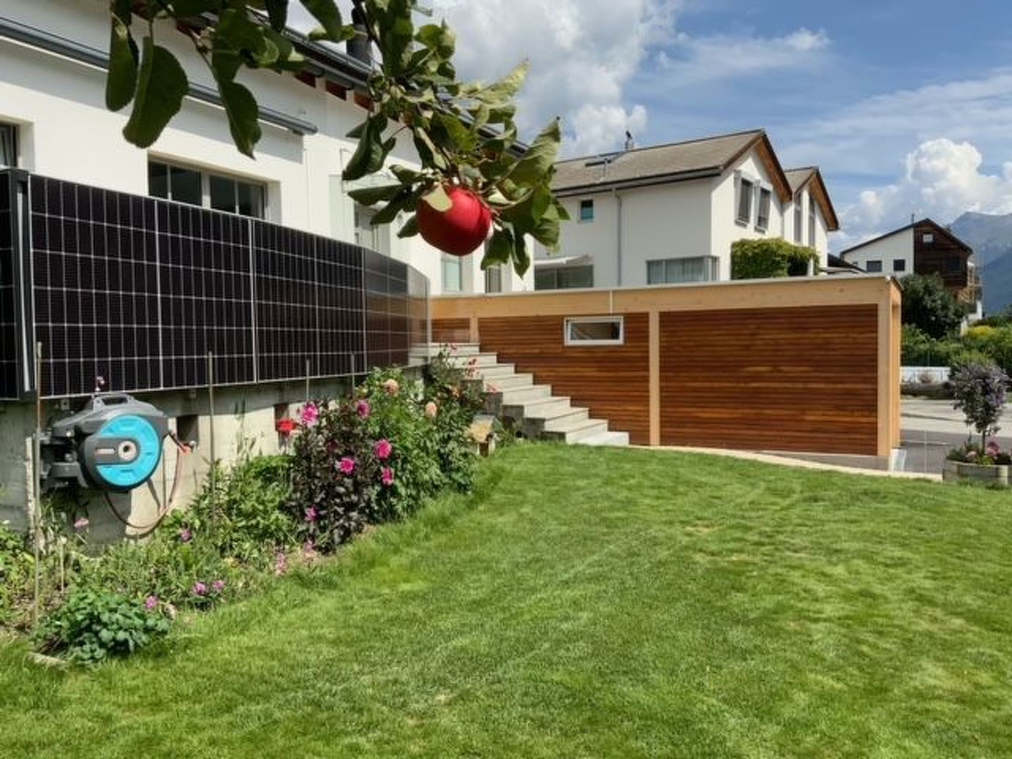 A residential property with a solar panel, a wooden fence, a staircase, and a well-maintained lawn.