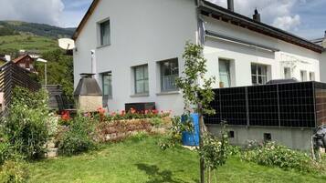 Ein modernes, zweistöckiges Haus mit weißer Fassade, einem Schornstein und einer Solaranlage.