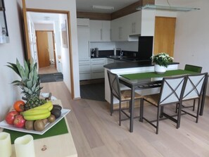 A modern kitchen with white cabinets, a black countertop, and a dining area with a table and chairs. - Schudel, (Scuol) by Interhome (Scuol)