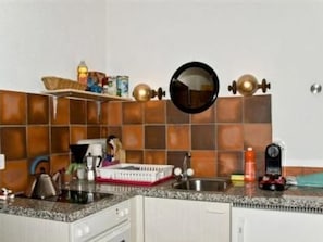 A kitchen with a granite countertop, a sink, and a stove. There are cabinets below the countertop.