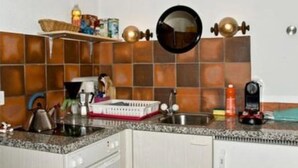 A kitchen with a tiled backsplash, a sink, a countertop with various items, and a hanging mirror. - Chasa Quirin, (Zernez) by Interhome (Zernez)