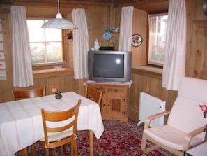 A cozy room with a television on a wooden cabinet, a dining table with chairs, and a patterned carpet. - Michael, (Valchava) by Interhome (Valchava)
