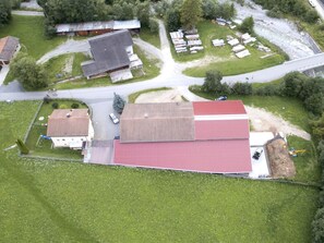 An aerial view of a residential area with multiple houses, a large red-roofed building, and a road. - Ferienwohnungen Paclerahof, (Sta. Maria - Santa Maria Val Müstair) by Interhome (Sta. Maria GR)