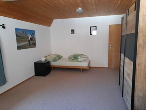 Una habitación con una cama, una mesita de noche, una puerta y un cuadro en la pared.