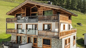 A two-story lodge with a wooden exterior, balconies, and a stone facade. - Avero Lodge by MEIN SAMNAUN – MOUNTAIN HOMES, (Samnaun-Compatsch) by Interhome (Samnaun)