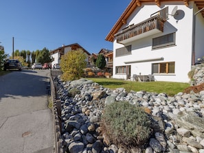 A residential area with a white house featuring a balcony, a stone wall, and a clear sky. - Wieser, (Sent) by Interhome (Sent)