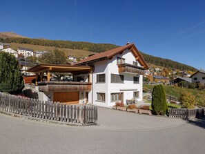 A two-story house with a balcony, a wooden deck, and a view of a hilly landscape. - Wieser, (Sent) by Interhome (Sent)