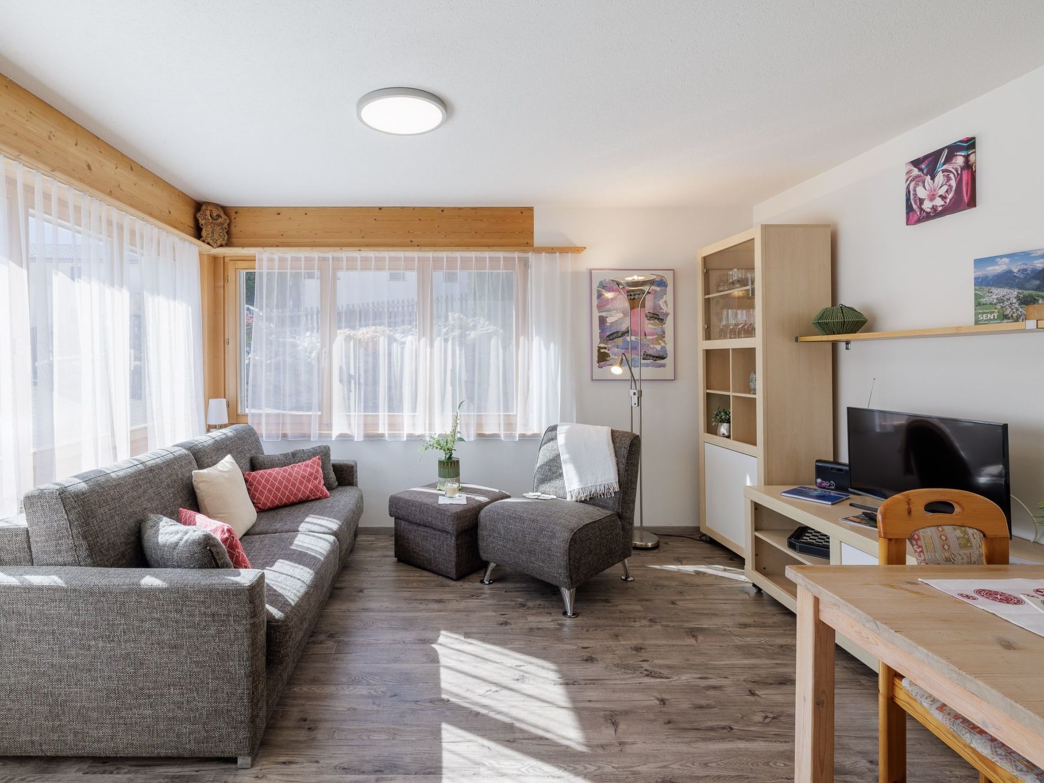 A furnished living room with a sofa, armchairs, a coffee table, and a TV.