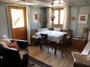 Ein gemütliches Zimmer mit Esstisch, Stühlen, einer Couch und einem kleinen Schrank.