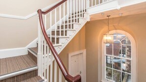 A staircase with white railings and a wooden handrail, carpeted steps, a door, and a window with a view of buildings. - Lower Park Row Apartments - Studio 4 - Hopewell (Bristol)