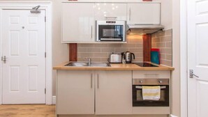 A compact kitchen with a built-in oven, a microwave, and a sink. - Lower Park Row Apartments - Studio 4 - Hopewell (Bristol)