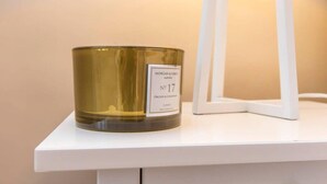 A candle on a white shelf with a label reading 'MORGAN & GRACE No 17 ORCHID & CHAMPION CANDLE.' - Lower Park Row Apartments - Studio 4 - Hopewell (Bristol)