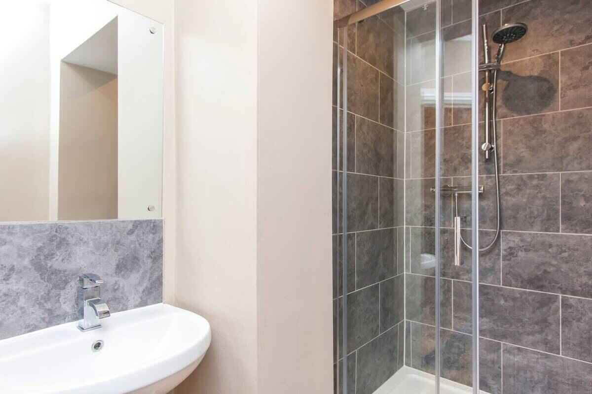 A bathroom with a white sink, a mirror, and a glass-enclosed shower area.