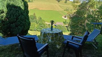 Eine Terrasse mit Tisch und Stühlen mit Blick auf eine grüne Landschaft.