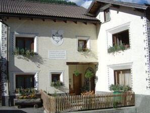 Edifici tradicional amb diverses finestres, una tanca de fusta i una placa que indica que és una casa d'hòsties.