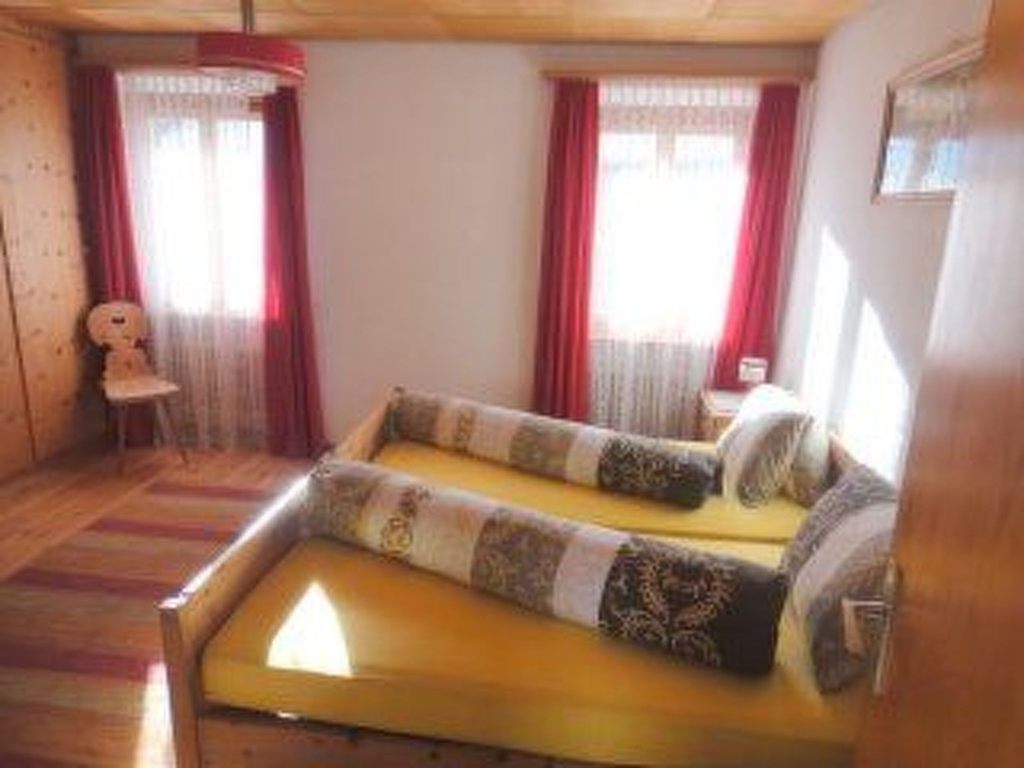 A room with a sofa bed, a chair, and a window with curtains.