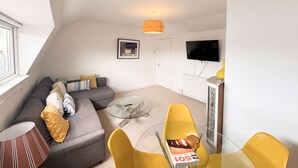 Ein modernes Wohnzimmer mit einer Couch, einem Glastisch und gelben Sesseln.
