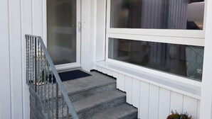Gradi que porten a una porta amb barana metàl·lica, una finestra amb vista a l'exterior i una porta amb panell de vidre.