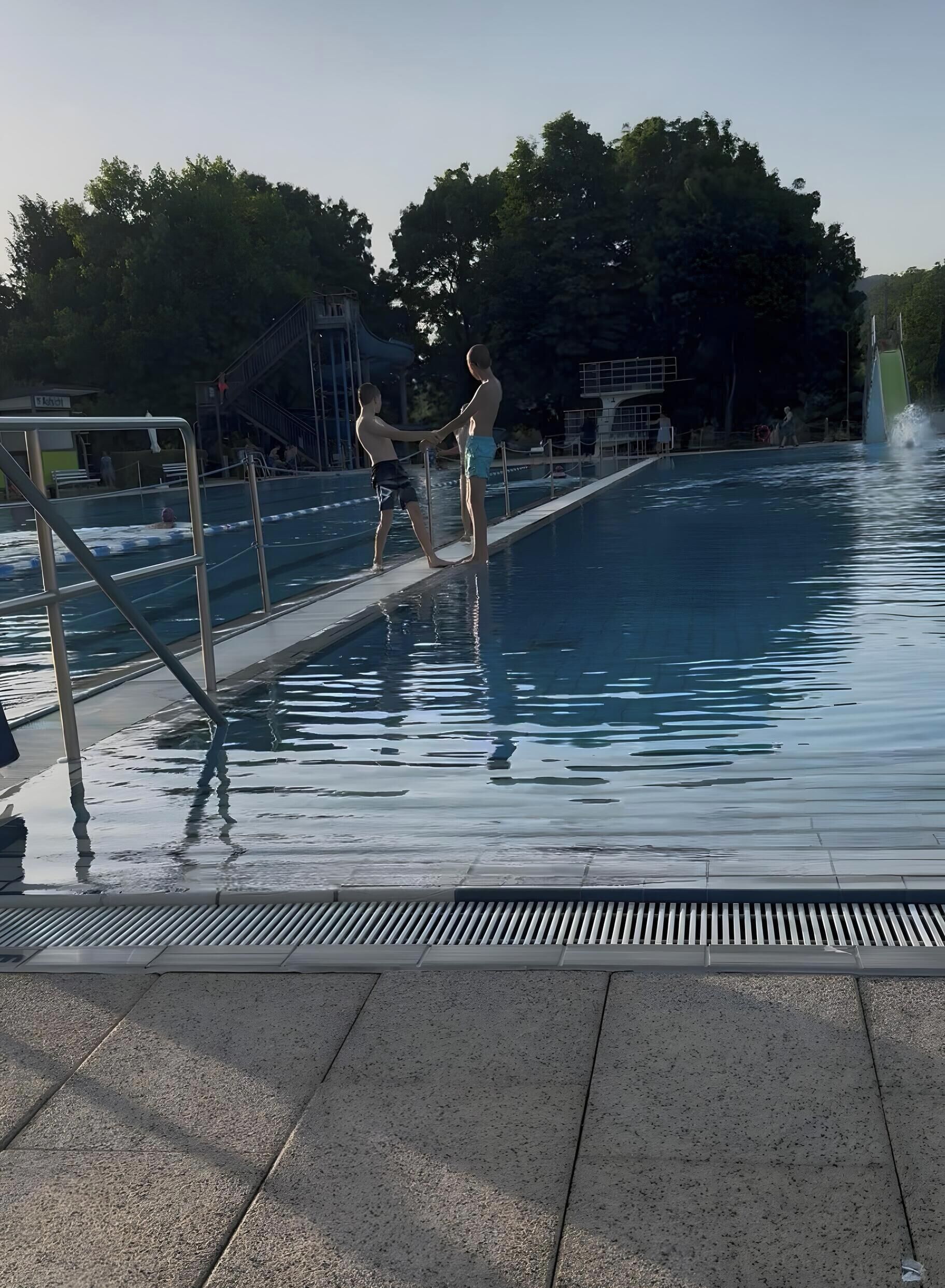 Een zwembad met duikplank en een badmeesterpost.