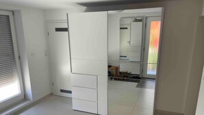 Habitació amb armari corredís, finestra amb persianes i sòl de rajola.