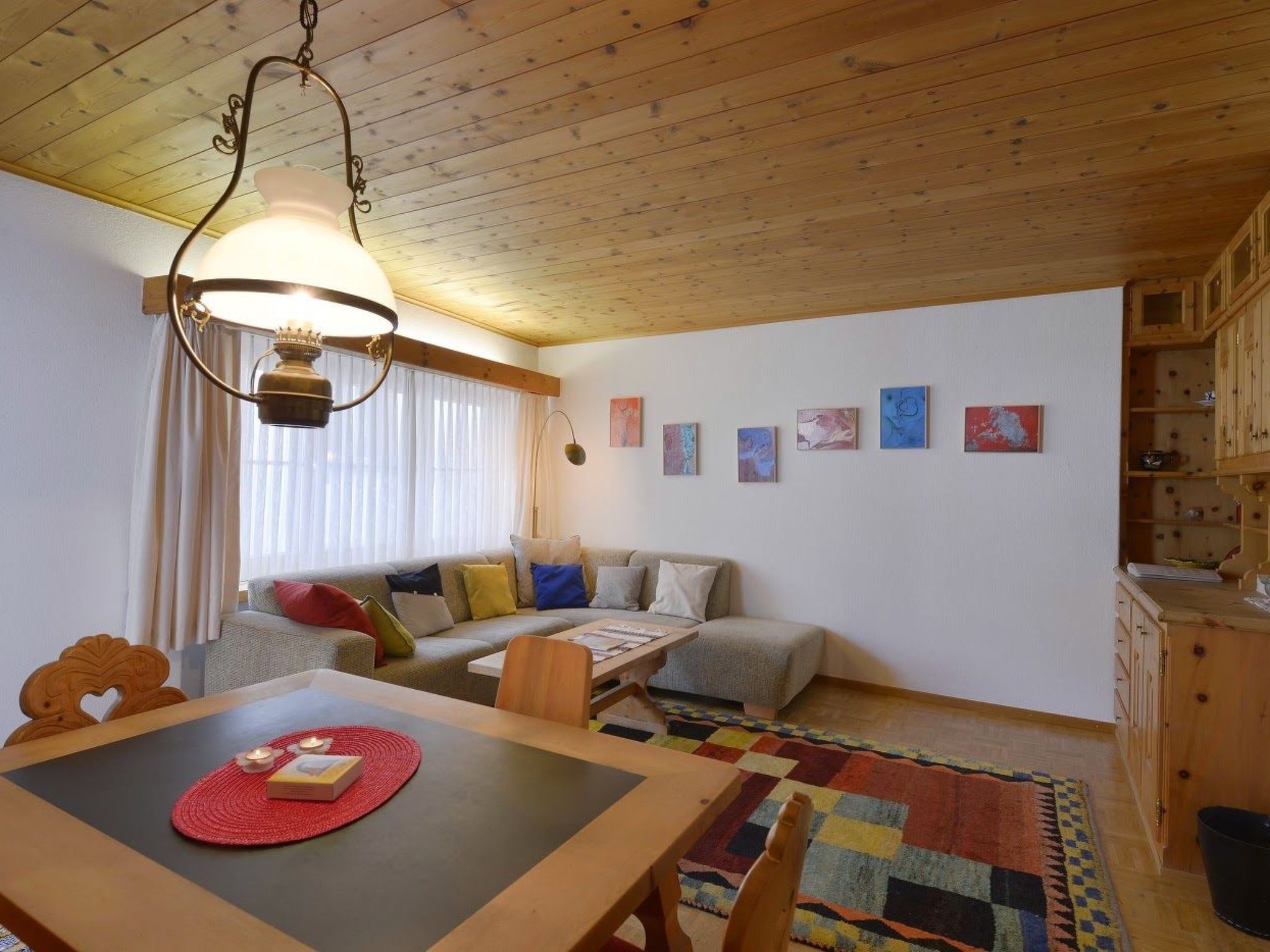 Een gezellige woonkamer met een bank, een eettafel met placemat en een kamerkleed met patroon.