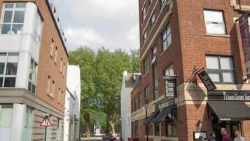 Une rue bordée d’immeubles, avec un passage piéton et un panneau indiquant une zone scolaire.