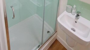 A bathroom with a glass-enclosed shower, a sink, and a mirror. - Prince Street Studio 6 (Bristol)