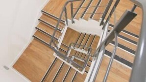 A modern staircase with a metal handrail and wooden steps. - Prince Street Studio 9 - Hopewell (Bristol)