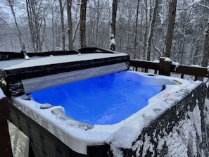 A hot tub surrounded by snow-covered trees.