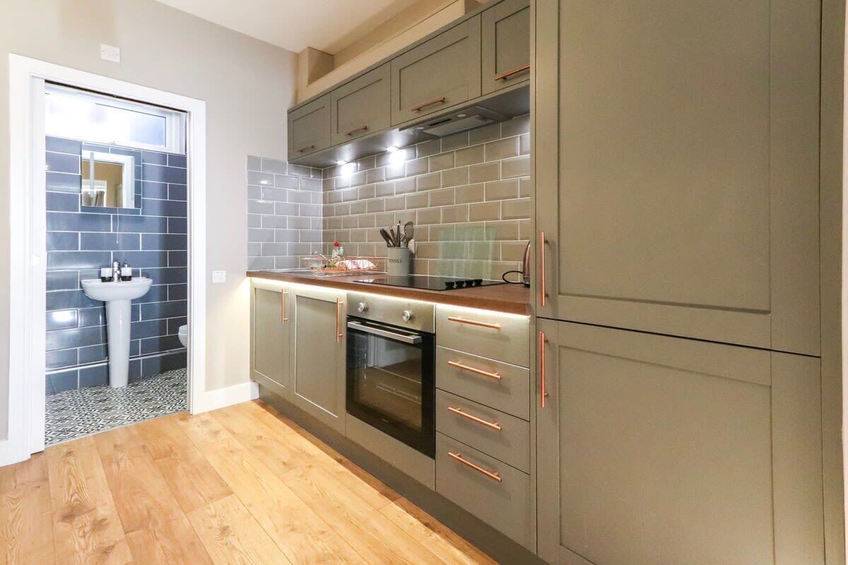 Een moderne keuken met grijze kastjes, een inbouwoven en een spoelbak.