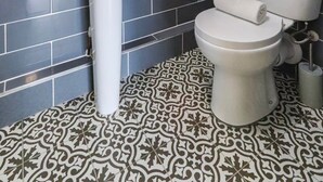 A bathroom with dark tiled walls, a white pedestal sink, a toilet, and patterned floor tiles. - Old Market Studios-No1 (City of Bristol)