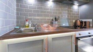 A modern kitchen with grey tiles, stainless steel appliances, and a wooden countertop. - Old Market Studios-No1 (City of Bristol)