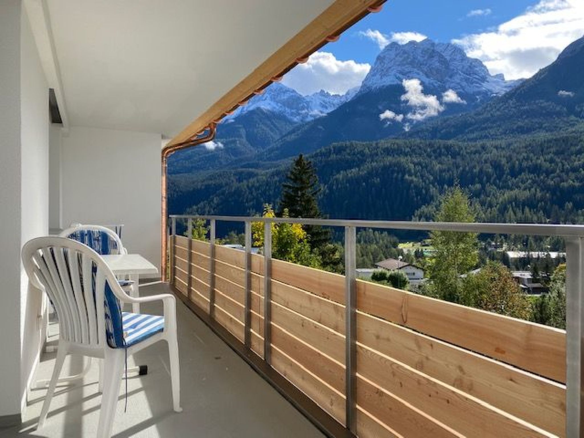 A balcony with a view of mountains, a table, and a chair.
