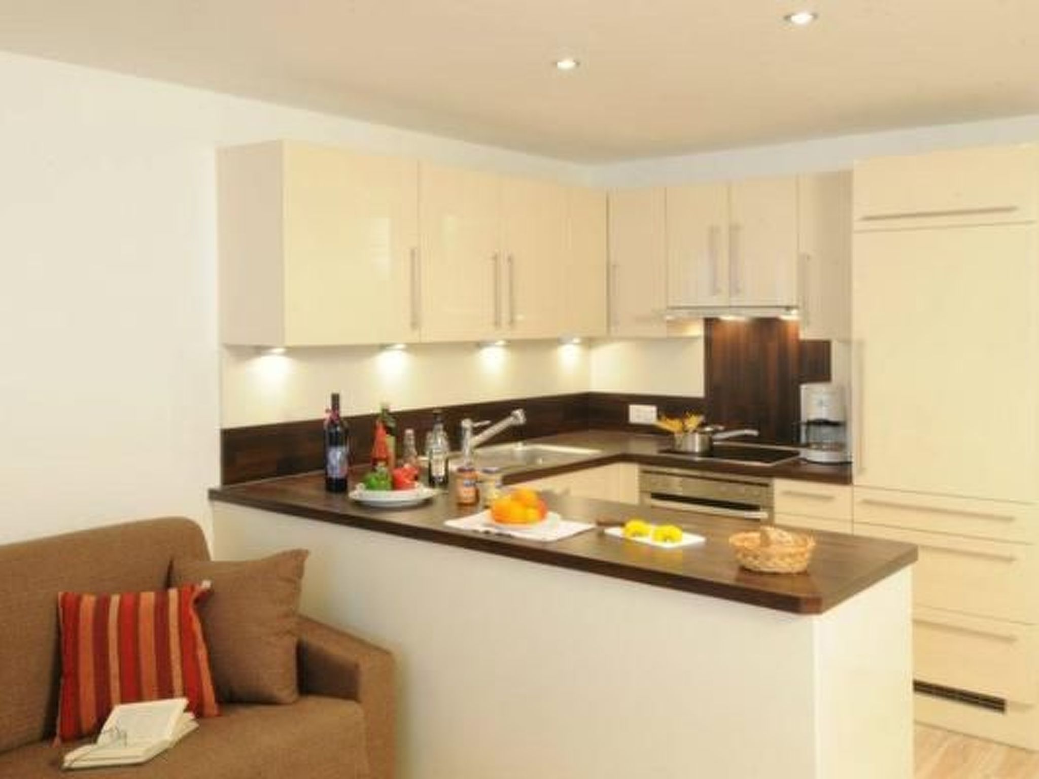 A modern kitchen with a central island, built-in cabinets, and a seating area with a sofa and cushions.