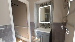 Een badkamer met een grijze wastafel, een spiegel en een douche.
