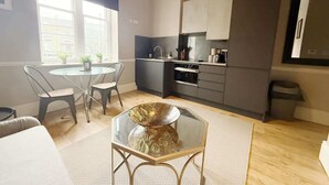 Een knus woongedeelte met een eethoek, kitchenette en een groot raam.