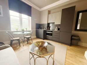 Un espace de vie compact comprenant un coin repas, une kitchenette et une grande fenêtre.