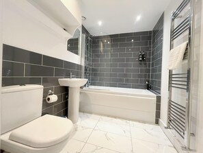 Ein modernes Badezimmer mit Toilette, Waschbecken und Badewanne.