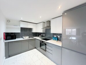 A modern kitchen with grey cabinets, a black stove, and a white countertop. - Anstey Heights - Apartment 09 - Hopewell (Easton)