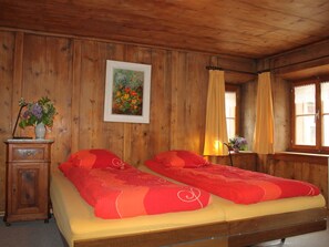 Ein Zimmer aus Holz mit zwei Betten, einem Gemälde, einer Blumenvase und einer Lampe.